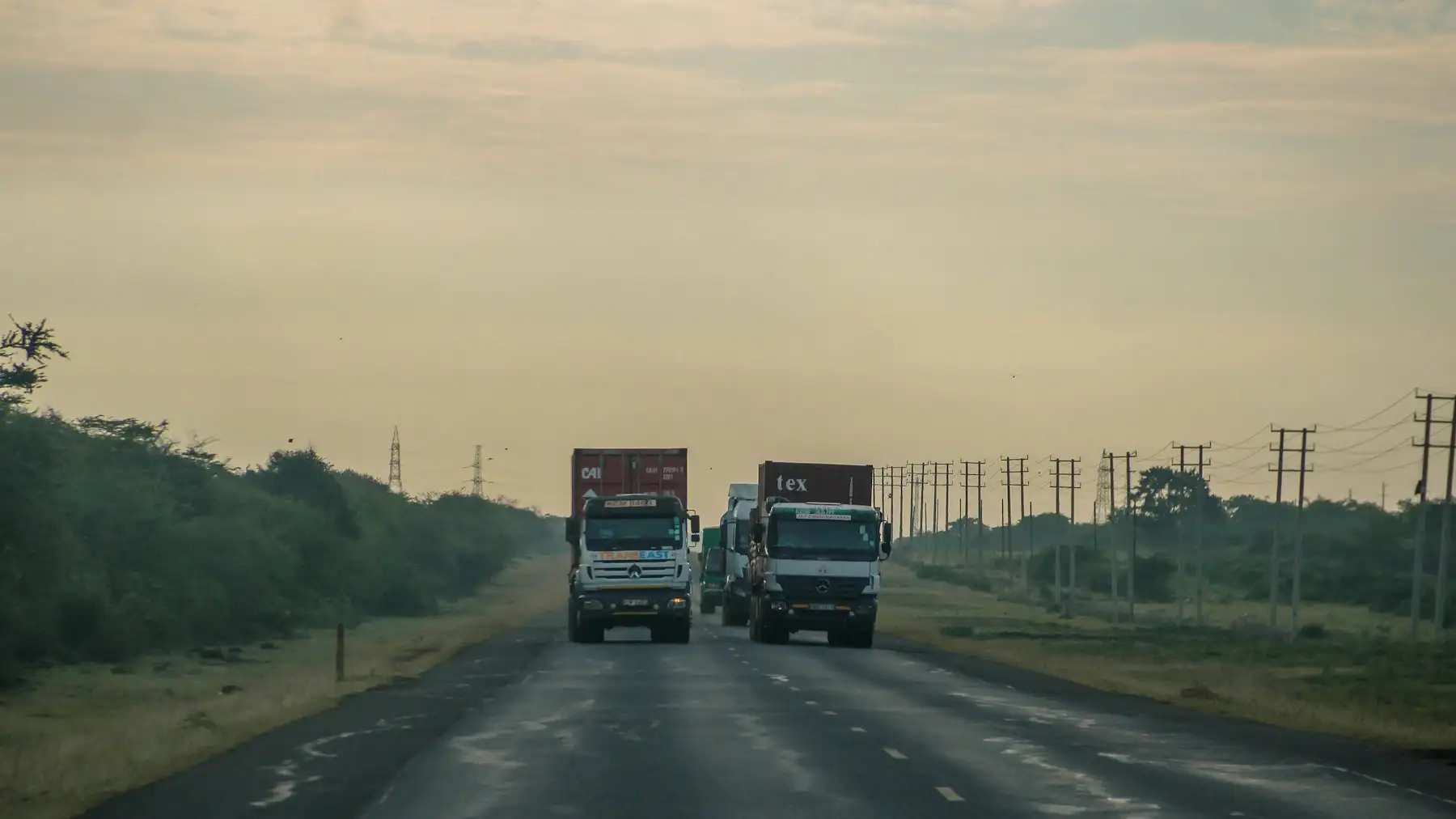Two cargo trucks on a long, straight road